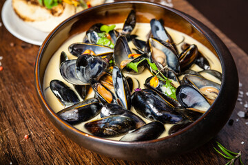 Blue mussels in cream wine sauce. Delicious healthy Italian traditional food closeup served for lunch in modern gourmet cuisine restaurant - obrazy, fototapety, plakaty