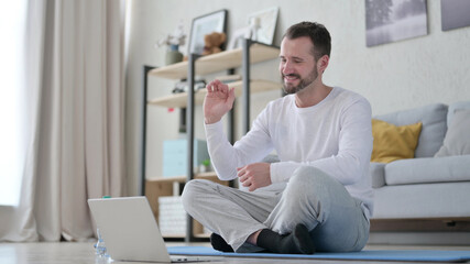 Mature Adult Man Talking on Video Call on Laptop while on Yoga Mat 