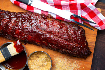A slab of Barbecue Pork Spare Ribs and sauce as top view on an old cutting board with sauce and...