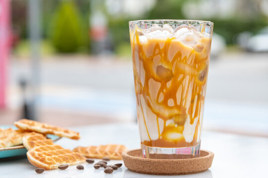 Iced caramel latte coffee in a tall glass with caramel syrup