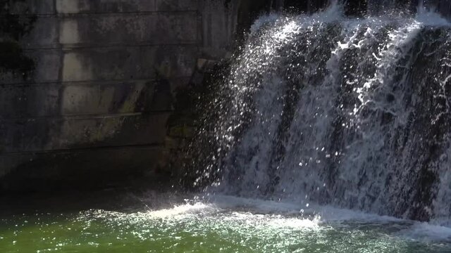 Industrielles Stauwehr mit spritzendem fallenden Wasser - Detail vor einer Betonwand