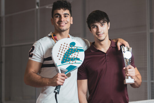 two boys paddle players posing with a trophy after having won a competition.