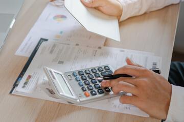 Close up hand of stress young asian businessman,male is pressing a calculator to calculate tax income and expenses, bills, credit card for payment or payday at home, office.Financial, finance concept.