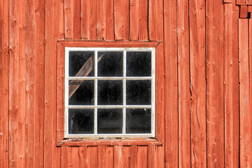Fototapeta na wymiar Window on a red weathered barn
