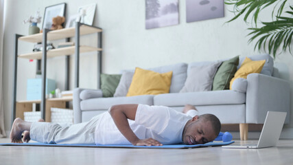 Fototapeta na wymiar Tired African Man doing Pushups on Yoga Mat at Home