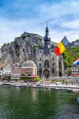 The historic town of Dinant with the Belgian flag and the citadelle on the rock and Collegiate Church of Notre-Dame at the Meuse river, Wallonia, Belgium - obrazy, fototapety, plakaty