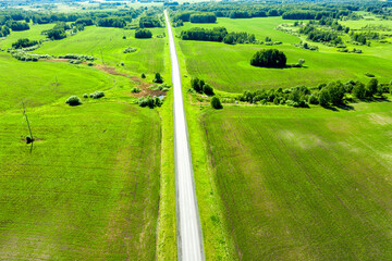 Highway through fields and arable land. View from above. Summer rural landscape