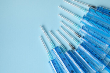 Disposable syringes with needles on light blue background, flat lay. Space for text