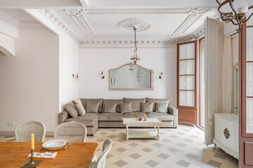 Classic living room with dining table, big sofa, tile floor, balcony and vintage chandeliers. Retro...