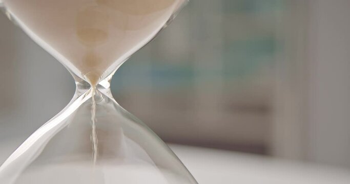 Hourglass or sandglass : Closeup view of golden sand falling down through a narrow neck in a sand clock or sand timer. Each hourglass measures and has specific duration of time. 4K DCI