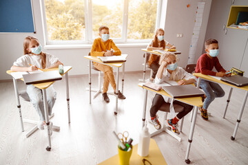 Fototapeta na wymiar School kids with notebooks sitting in classroom together