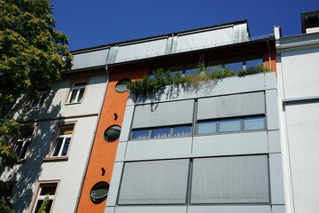 Modernes Wohnhaus mit hellgrauem Sonnenschutz im Sommer bei blauem Himmel und Sonnenschein im...