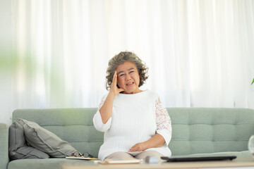 Asian Elderly senior woman sudden headache and migraine so pain and illness on sofa alone at home,Pensioner stress and headache painful,Elderly Care and insurance Concept