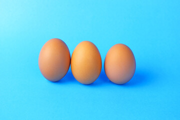 
Three fresh chicken eggs on a blue background