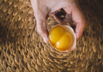 Person holding a raw egg with two yolks