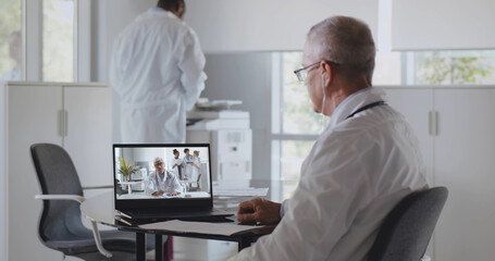 Mature male doctor having video conference with colleague sitting in clinic office