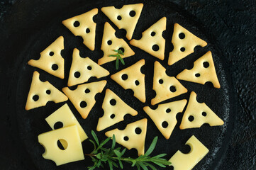 Cookies in the form of pieces of cheese on a black background. Top view, flat lay