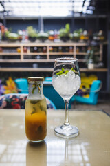 Vertical shot of a cold drink in a small bottle next to a glass full of ice on a blurry background