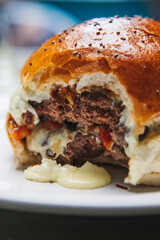 Vertical closeup of a delicious cheeseburger with a bite mark in it on a blurry background
