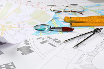 Office stationery, magnifying glass and folding ruler on cadastral maps of territory with buildings