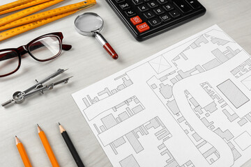 Office stationery and cadastral map of territory with buildings on white wooden table