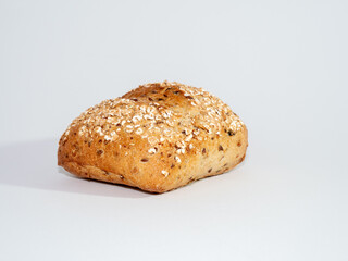 Baked bun soaked in sesame seeds and oatmeal isolated on white background. 
