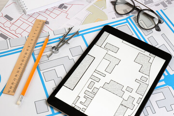 Office stationery, tablet and eyeglasses on cadastral maps of territory with buildings