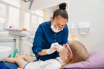Obraz na płótnie Canvas the dentist examines the mouth of a kid girl. 