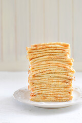 Traditional Russian Crepes Blini stacked in a white plate on light background. Maslenitsa traditional Russian festival meal. Russian food, russian kitchen