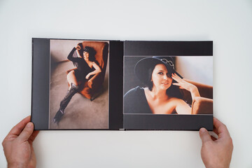 hands holding a open photobook from photo shoot of an woman on white background.