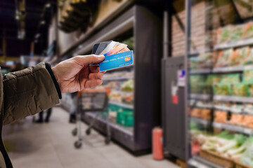 Young male customer making payment with credit card in grocery shop