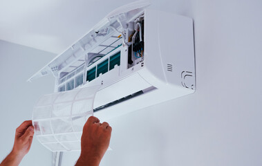 Air conditioner repair and maintenance. A man holds an air conditioner filter in his hands.