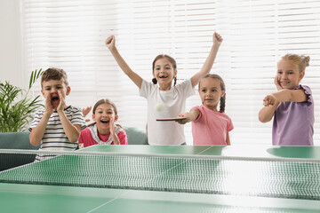 Cute happy children playing ping pong indoors