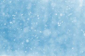 Abstract Christmas background with snowflakes during snowfall on blurred background