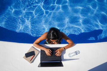 bird view of remote online working digital nomad woman in bikini with long black hair and laptop on...