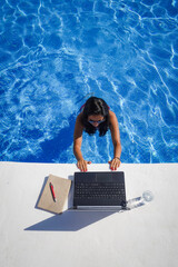 bird view of remote online working digital nomad woman in bikini with long black hair and laptop on...
