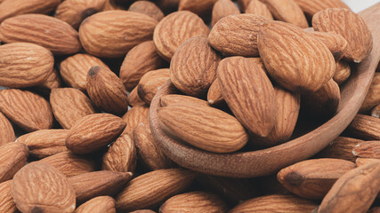Background of almonds scattered and wood spoon, Almonds in wooden spoon, Background of almonds scattered.