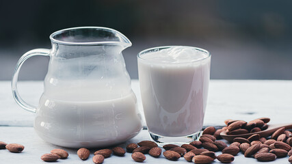 Almond milk in glass and almonds seeds on the wooden table, Healthy food and drink concept.