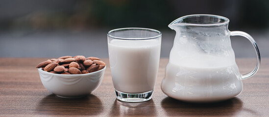 Almond milk in glass and almonds seeds on the wooden table, Healthy food and drink concept.