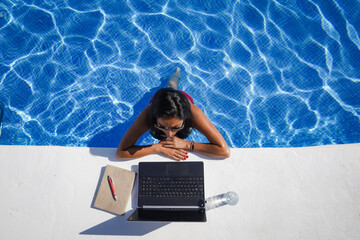 bird view of remote online working digital nomad woman in bikini with long black hair and laptop on...