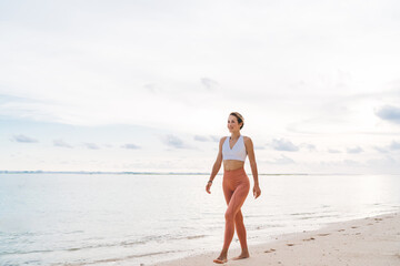 Sporty female walking barefoot along sea