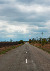 The road runs through the countryside and abuts the horizon.