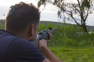 A young guy is preparing to shoot from a pneumatic weapon.