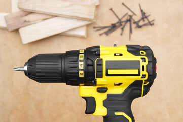 The yellow-black screwdriver on wood background, screws.