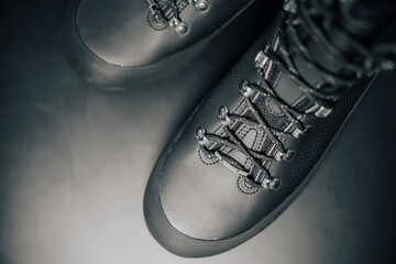 Detail of a black leather shoe on a black background. Stylish, fashionable and designed boot with laces. Abstract fashion close-up of outdoor boots with rubber protection. Background image.