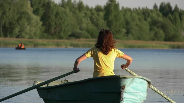 Woman rows boat along on lake. Woman padding boat on lake. Vacation. Travel. Relax. Active rest. 