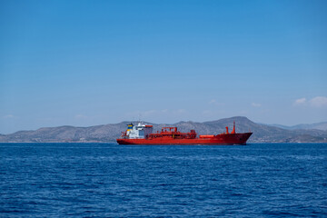 Chemical oil tanker ship, red color in blue Aegean sea and sky background. Greece