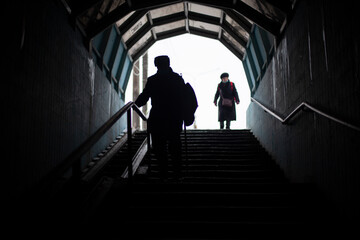People go down the stairs. Silhouettes of people in the tunnel.