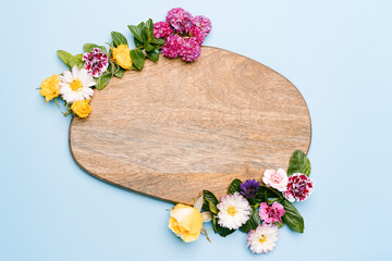Wooden piece decorated with flowers on a pastel blue background. Top view mockup with copy space.