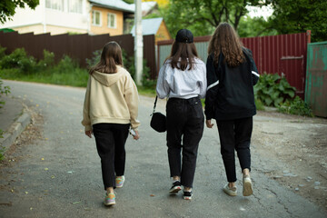 Three girls are walking down the road. Teenagers in the countryside.